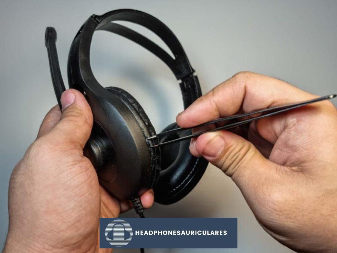Inserte su herramienta de palanca en el espacio entre la almohadilla y la base de los auriculares con cuidado.