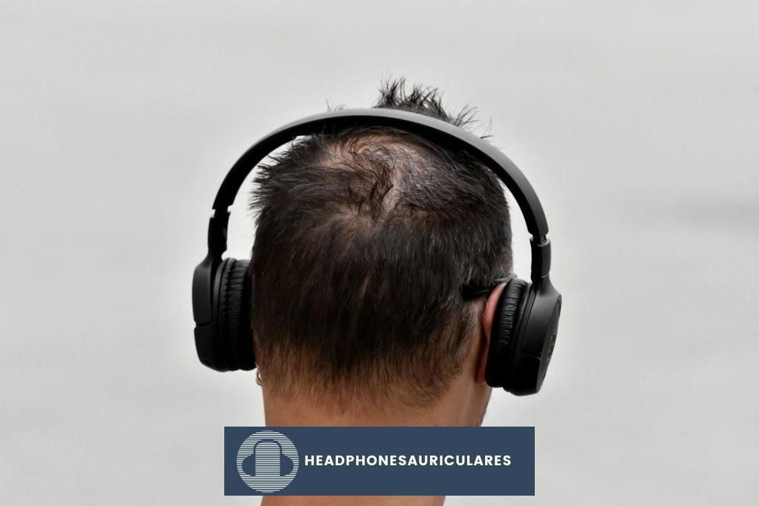 Vista posterior de un hombre que usa audífonos en la oreja (De: Pixnio)