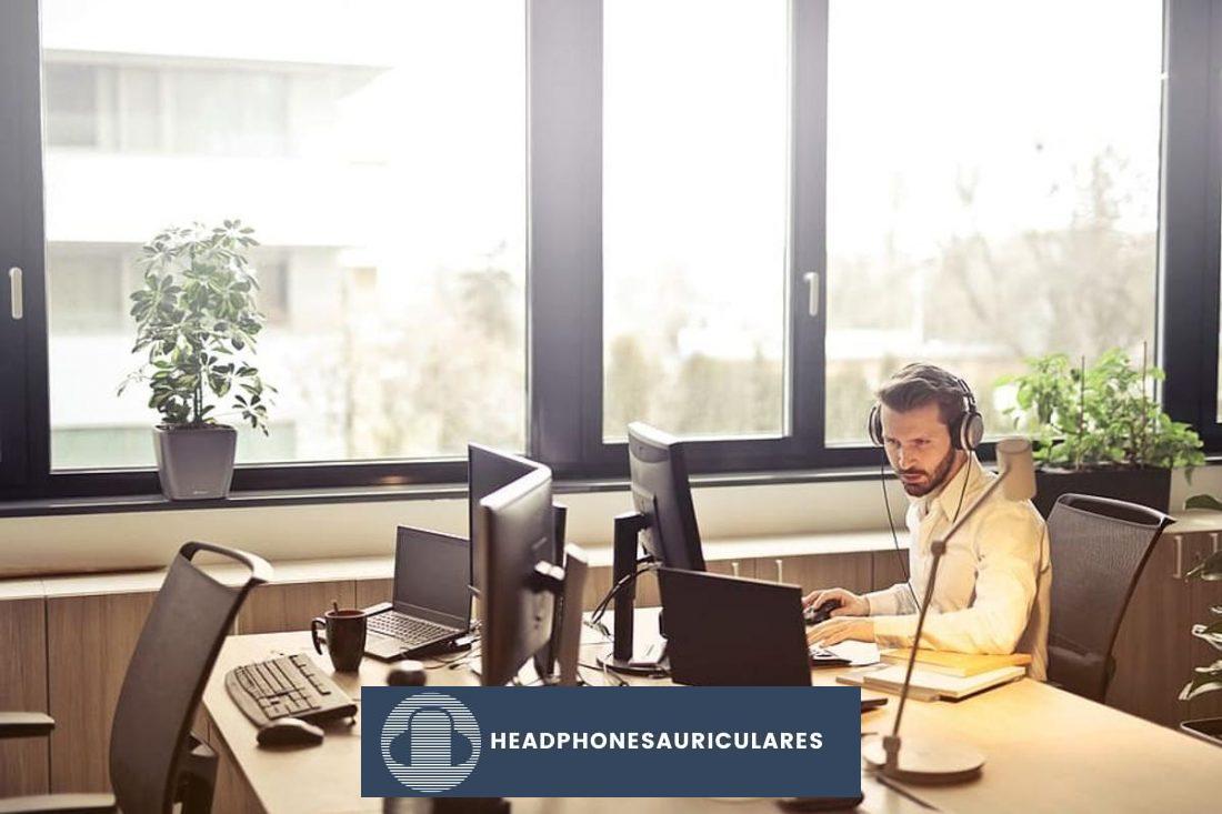 Hombre con camiseta amarilla escuchando música con auriculares mientras trabaja solo (De: Pxfuel.com)