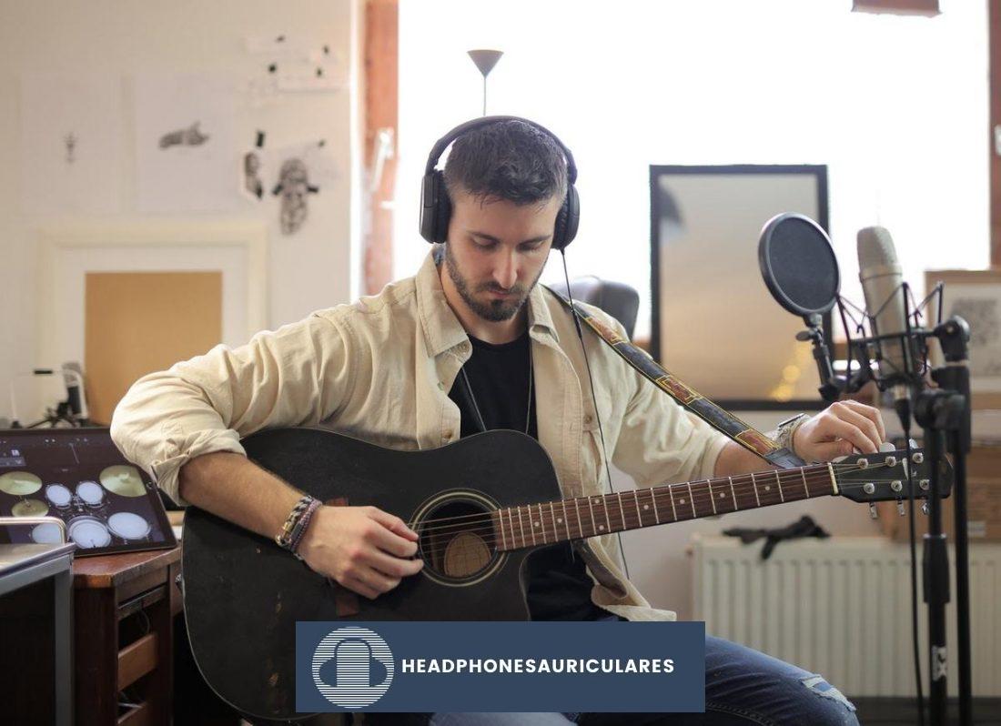 Un hombre toca la guitarra con los auriculares puestos (De Pexels.com)