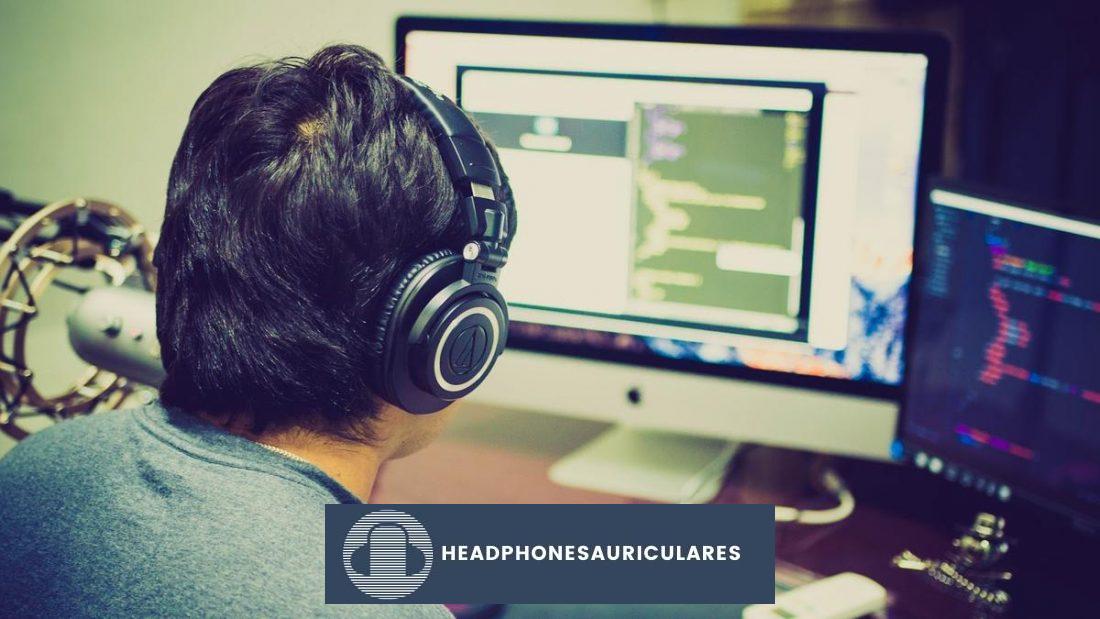 Hombre usando audífonos y trabajando en una Mac (De: Pexels)