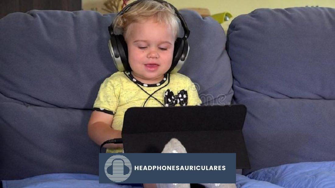 Niño pequeño viendo algo en el iPad con auriculares (de dreamstime.com)