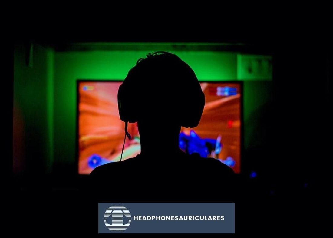 Gamer usando auriculares para juegos mientras juega (De: Pxfuel)