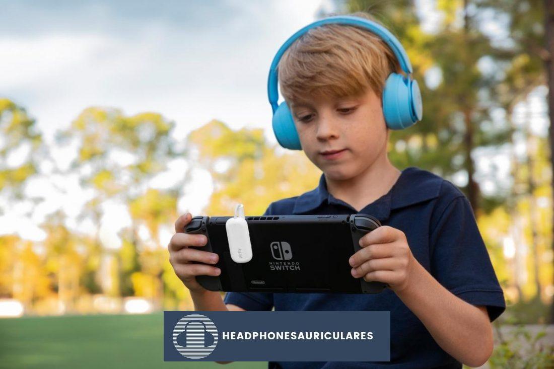 Un niño usando audífonos mientras juega con un dispositivo (De newatlas.com)